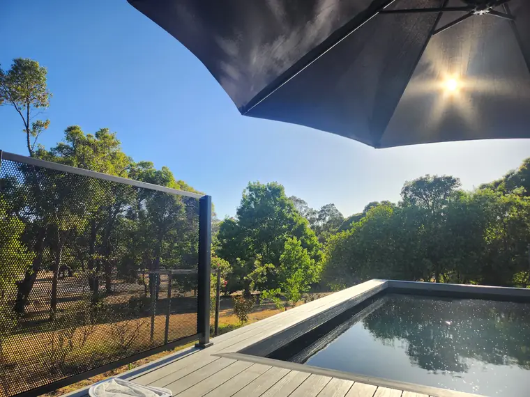 A pool deck above the bush. The panel on the drop edge does both jobs.