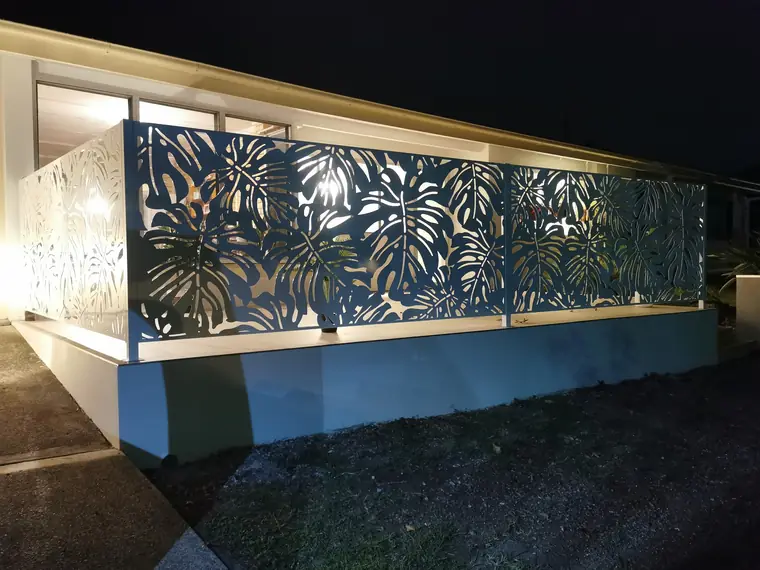 White Monstera panels around a raised terrace, lit at night.